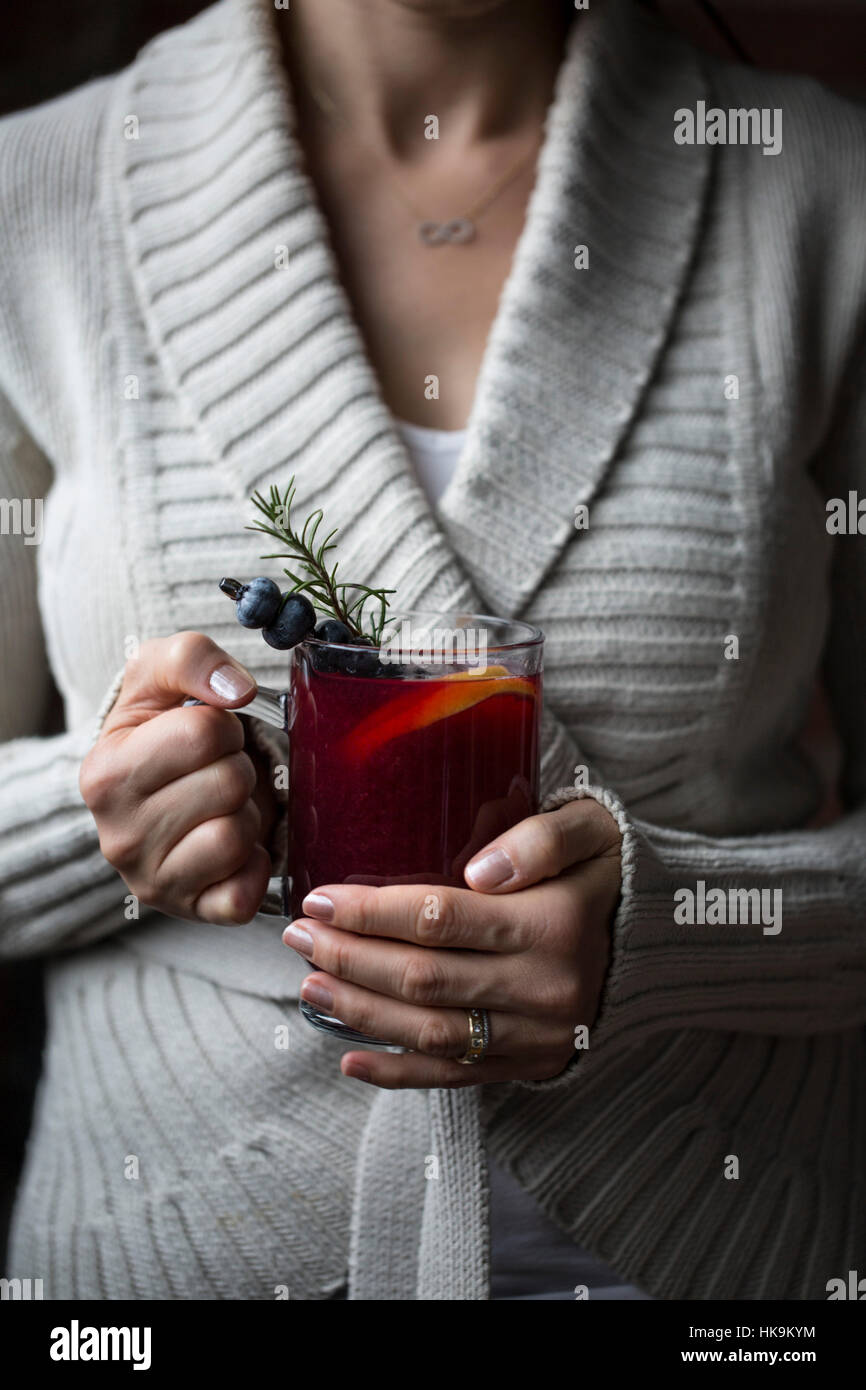 Una donna è fotografato con un bicchiere di mirtillo hot toddy in mano Foto Stock