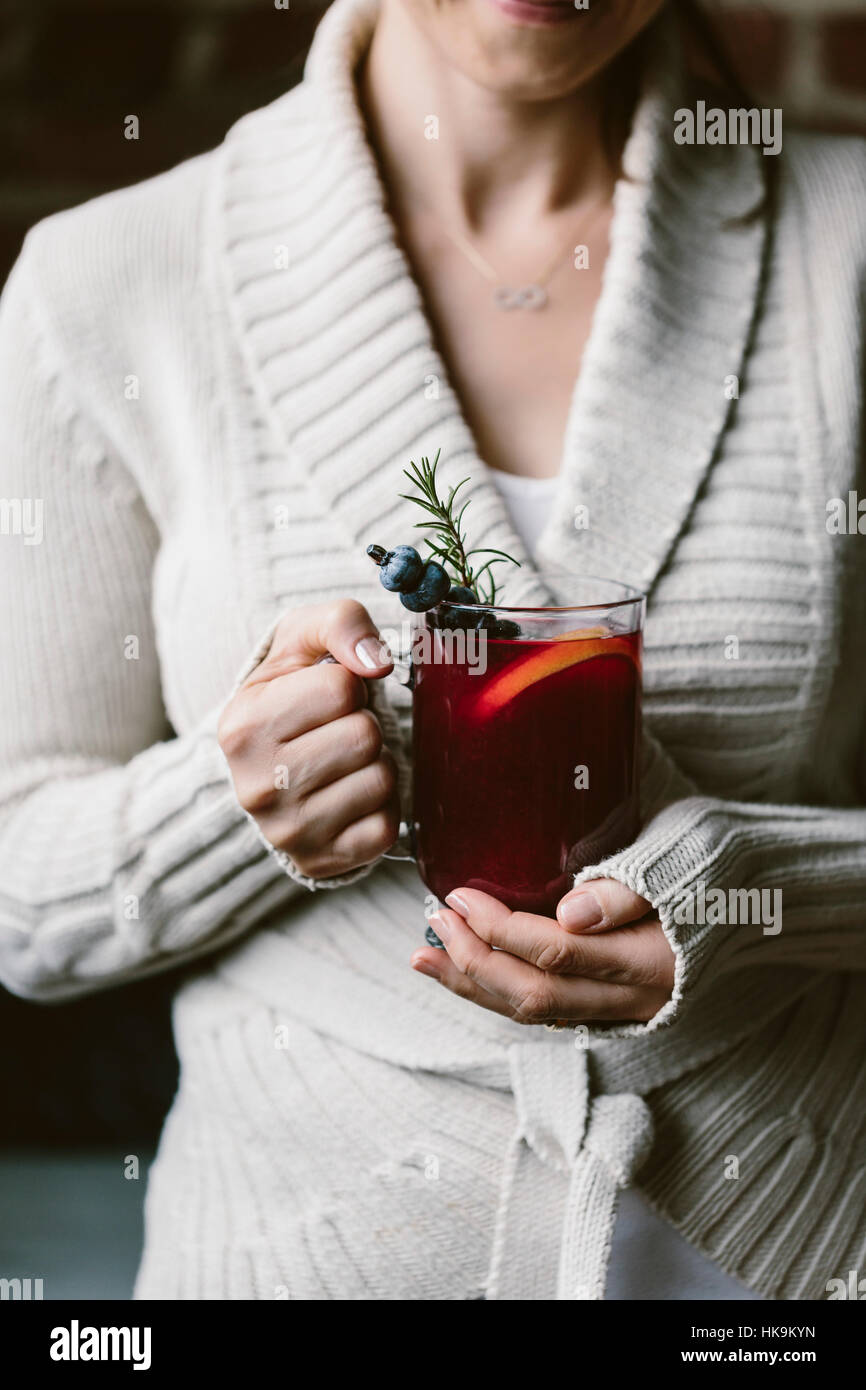 Una donna è fotografato con un bicchiere di mirtillo hot toddy in mano Foto Stock