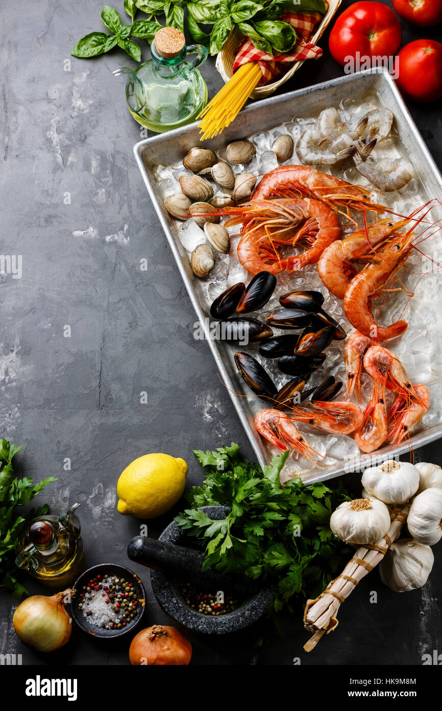 Materie piatti a base di frutti di mare freschi cocktail con Vongole e gamberetti e gli ingredienti per cucinare la pasta Spaghetti su sfondo di calcestruzzo Foto Stock