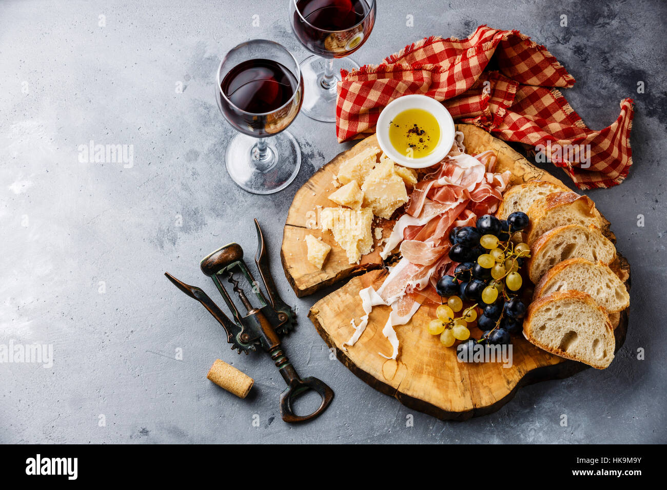 Piatto antipasto con prosciutto, parmigiano, pane e vino sul cemento grigio sfondo Foto Stock