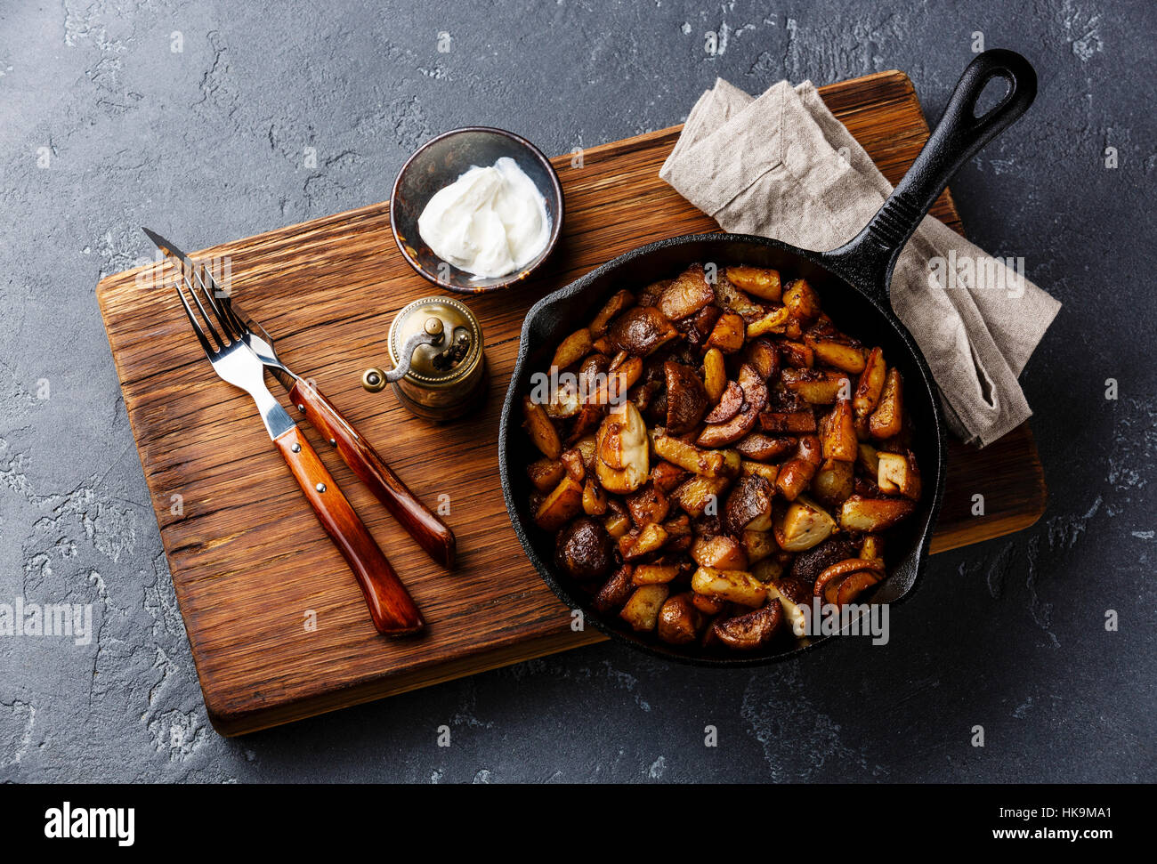 Frittelle di patate arrosto con porcini funghi selvatici in ferro nero padella in pietra scura sullo sfondo Foto Stock