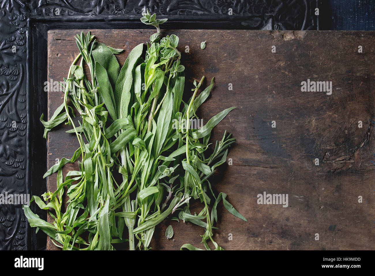 Bundle di fresche erbe italiano rosmarino, origano e salvia su un vecchio legno scuro e nero ornati in background. Vista da sopra con lo spazio di copia Foto Stock