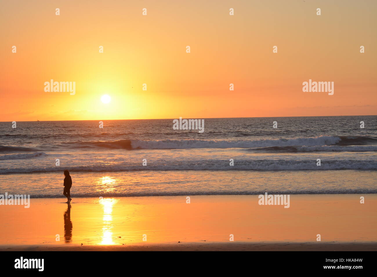 Passeggiate in spiaggia sotto un tramonto Foto Stock