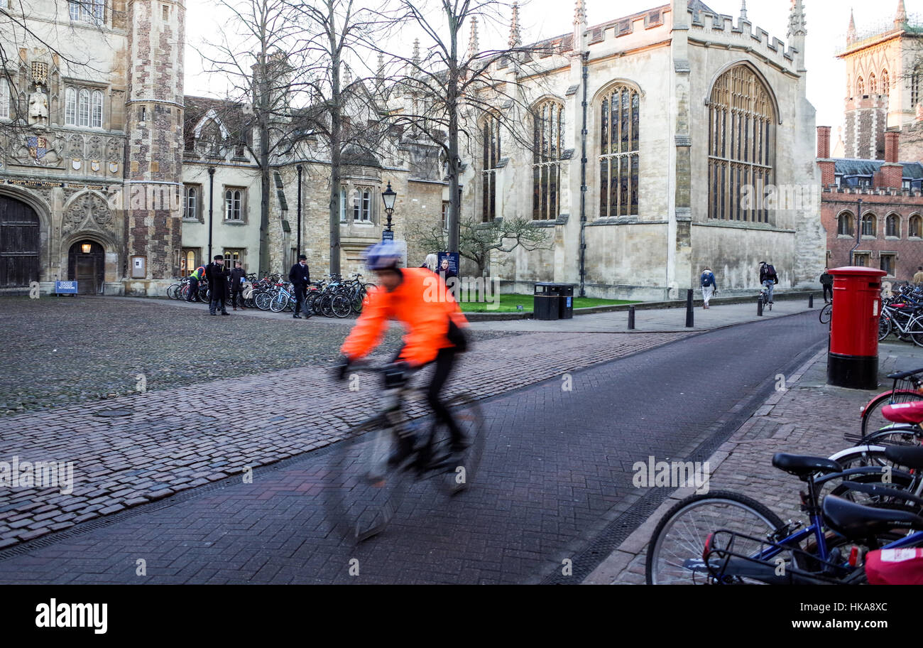 Un vestito luminosamente ciclista passeggiate attraverso Trinity Street nel centro storico di Cambridge Foto Stock