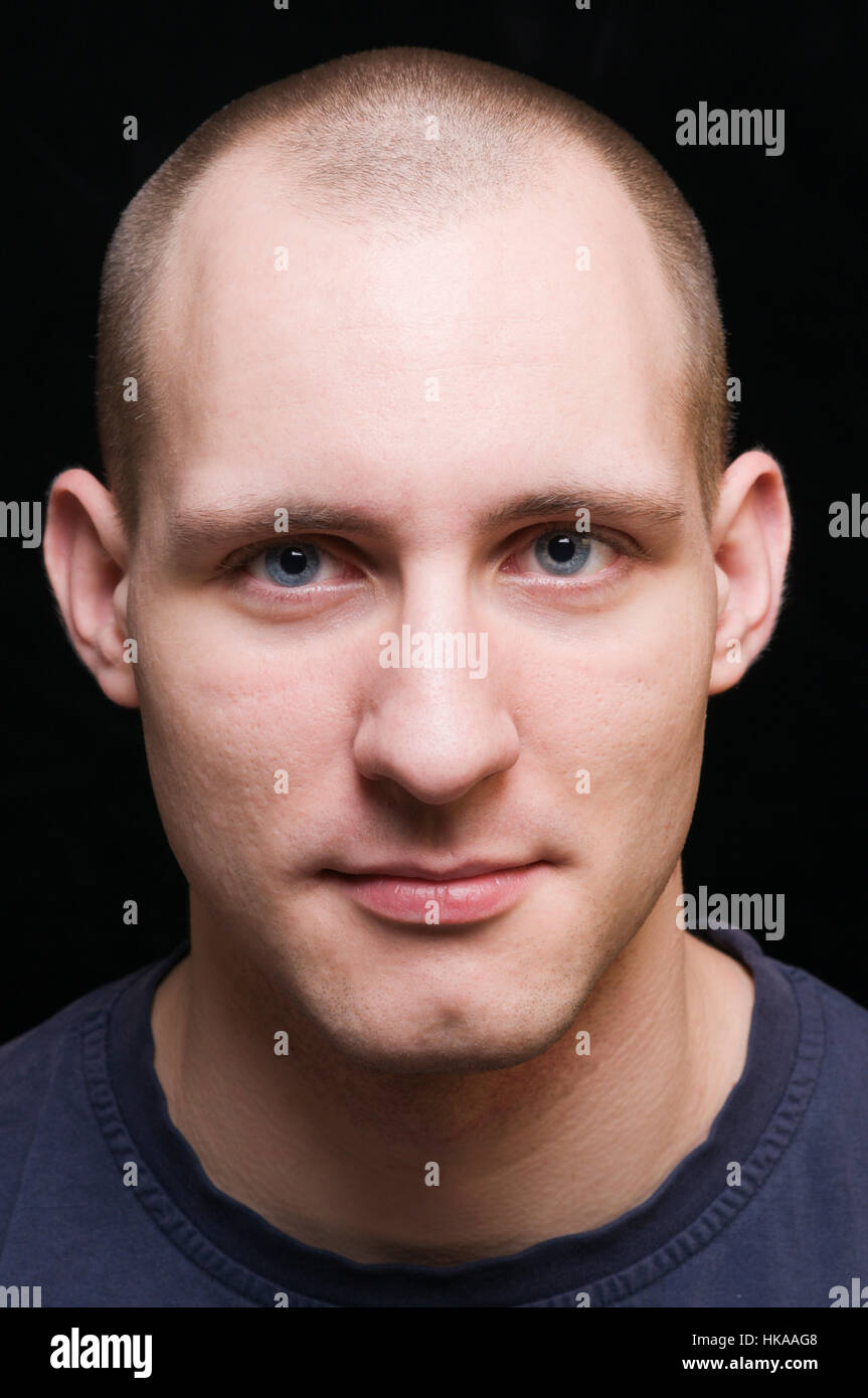 Faccia frontale ritratto di un giovane uomo contro uno sfondo nero arditamente sorridente nella fotocamera. Foto Stock