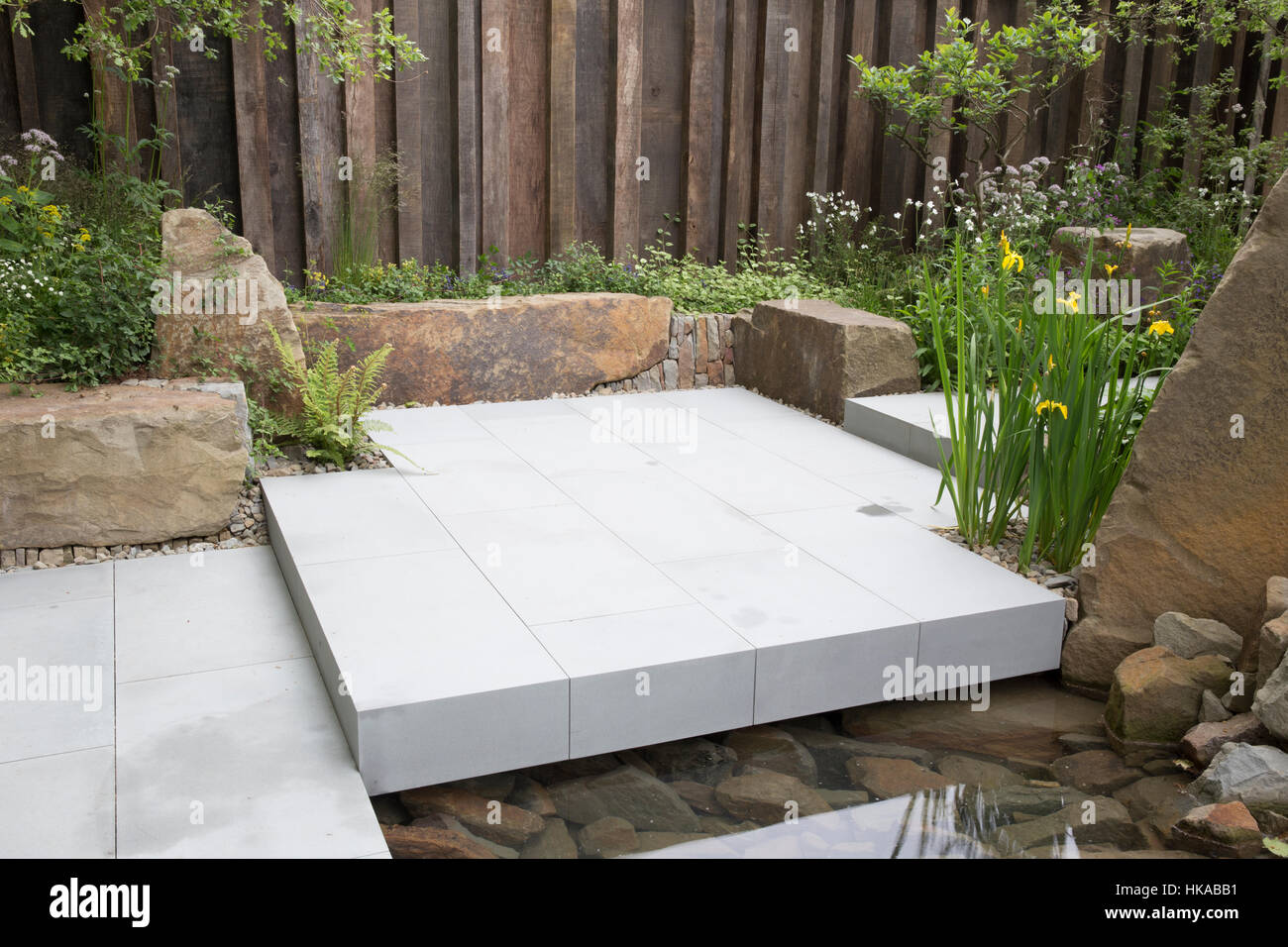 M&G giardino, vista della Foresta di Dean pietra banco di boulder e patio, rovere parete giardino, acqua caratteristica, Iris - Designer Foto Stock