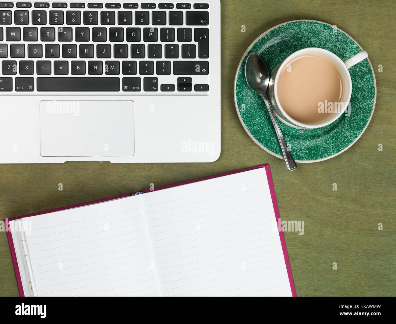 Un moderno Business o il Creative workstation su un verde da scrivania con un computer portatile n. Persone con un fustellato aperto il notebook e tè o caffè Foto Stock