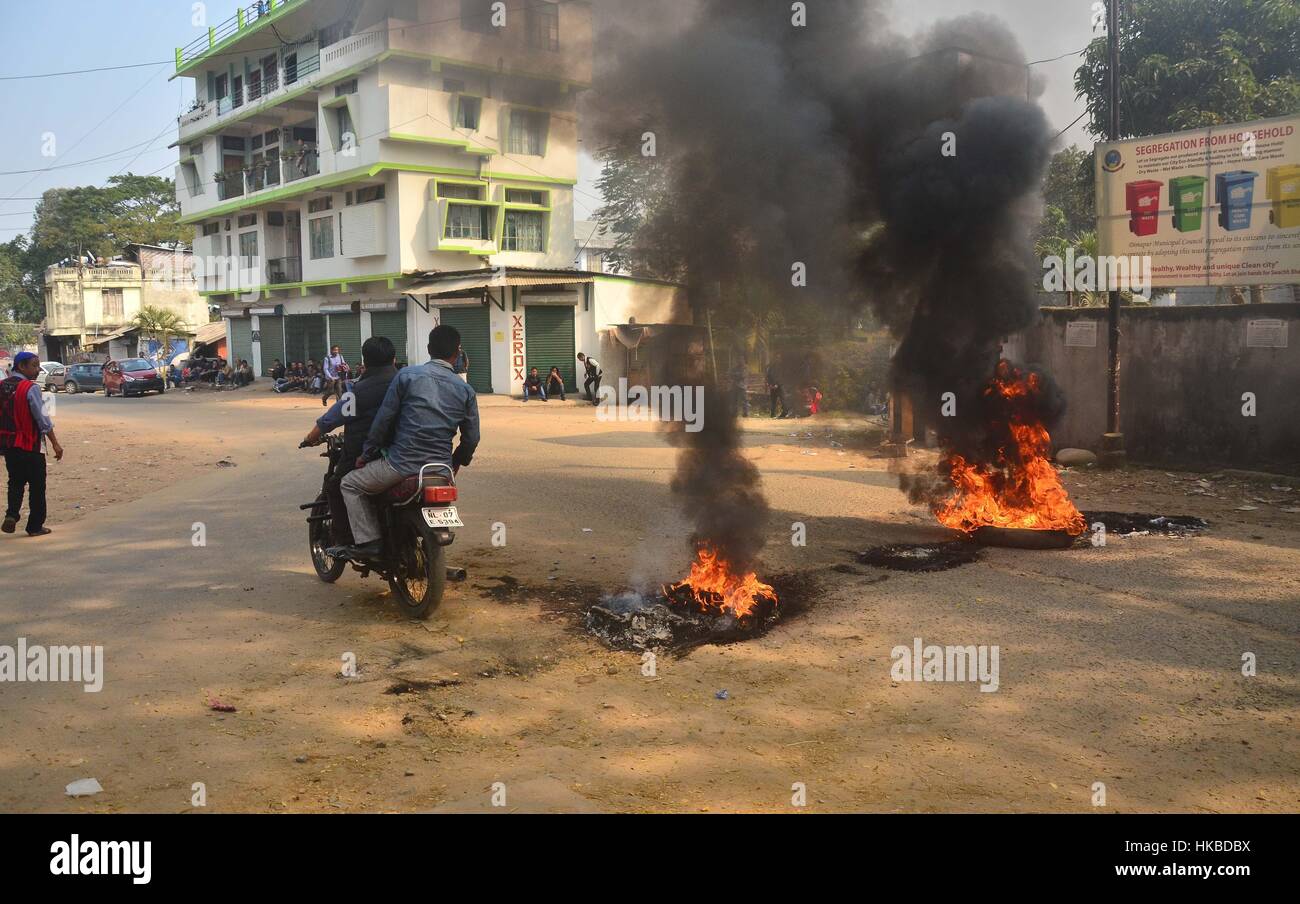 Dimapur, India 28 Gennaio 2017: un automobilista passa azionamenti pneumatici masterizzazione messa su strada mediante bandh sostenitori durante un totale stato ampia shutdwon chiamata dal comitato di coordinamento congiunto contro il 33% di donne la prenotazione per la prossima comunale urbano e locale del corpo elettorale in stato di Dimapur, India nord orientale di stato del Nagaland. Credito: Caisii Mao/Alamy Live News Foto Stock