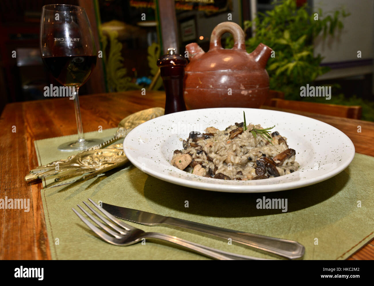 Risotto al funghi (funghi) con un bicchiere di vino rosso Foto Stock