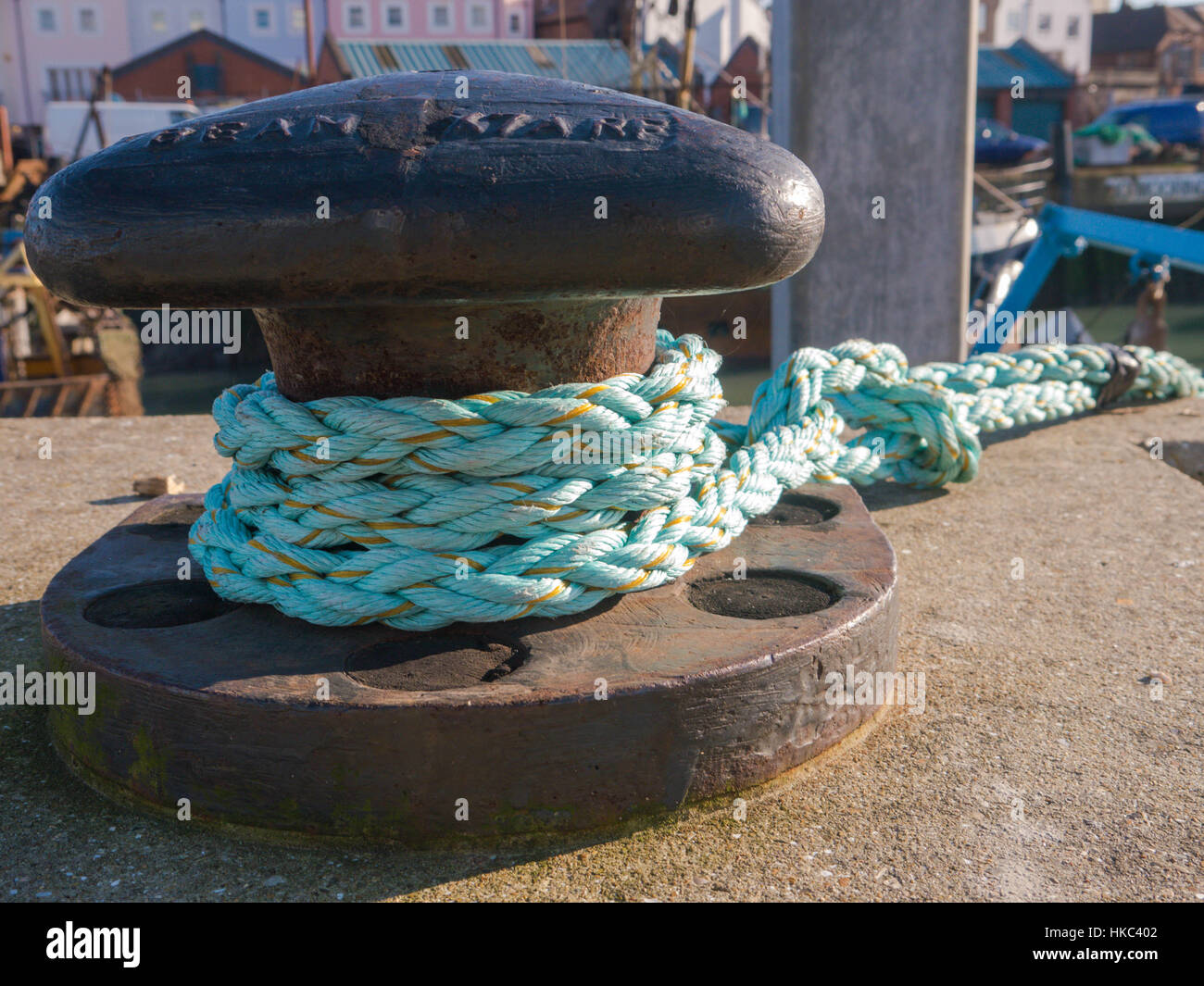 L'uomo fatto di fibre di fissaggio corda di una barca per una bollard su un molo Foto Stock