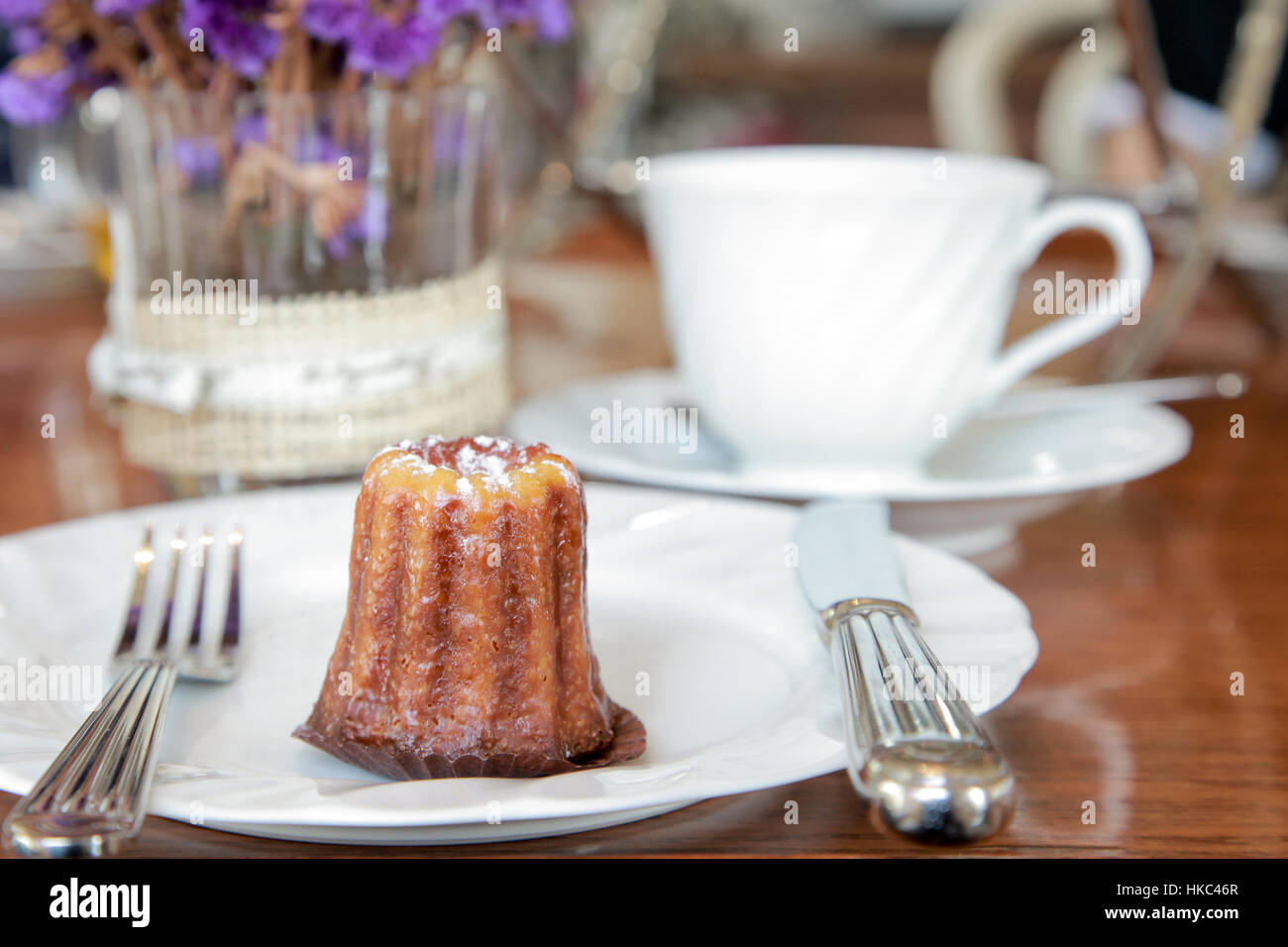Piccolo pezzo di canele servire in un piatto sul tavolo in tea shop Foto Stock