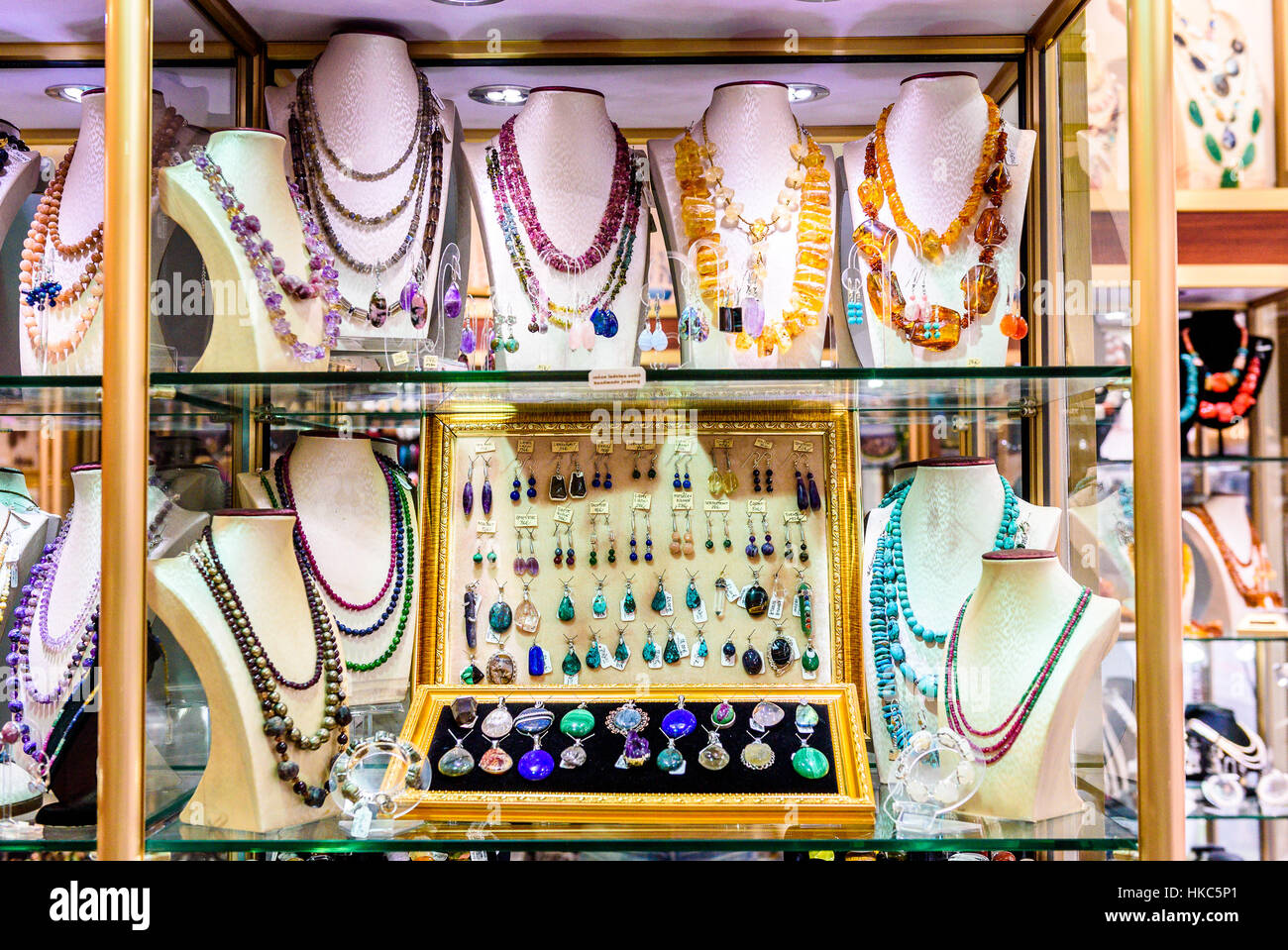 Display con diversi disegni di gioielli fatti a mano su supporto. Close-up di gioielli fatti a mano shop window display. Varietà di orecchini, collane, anelli, b Foto Stock