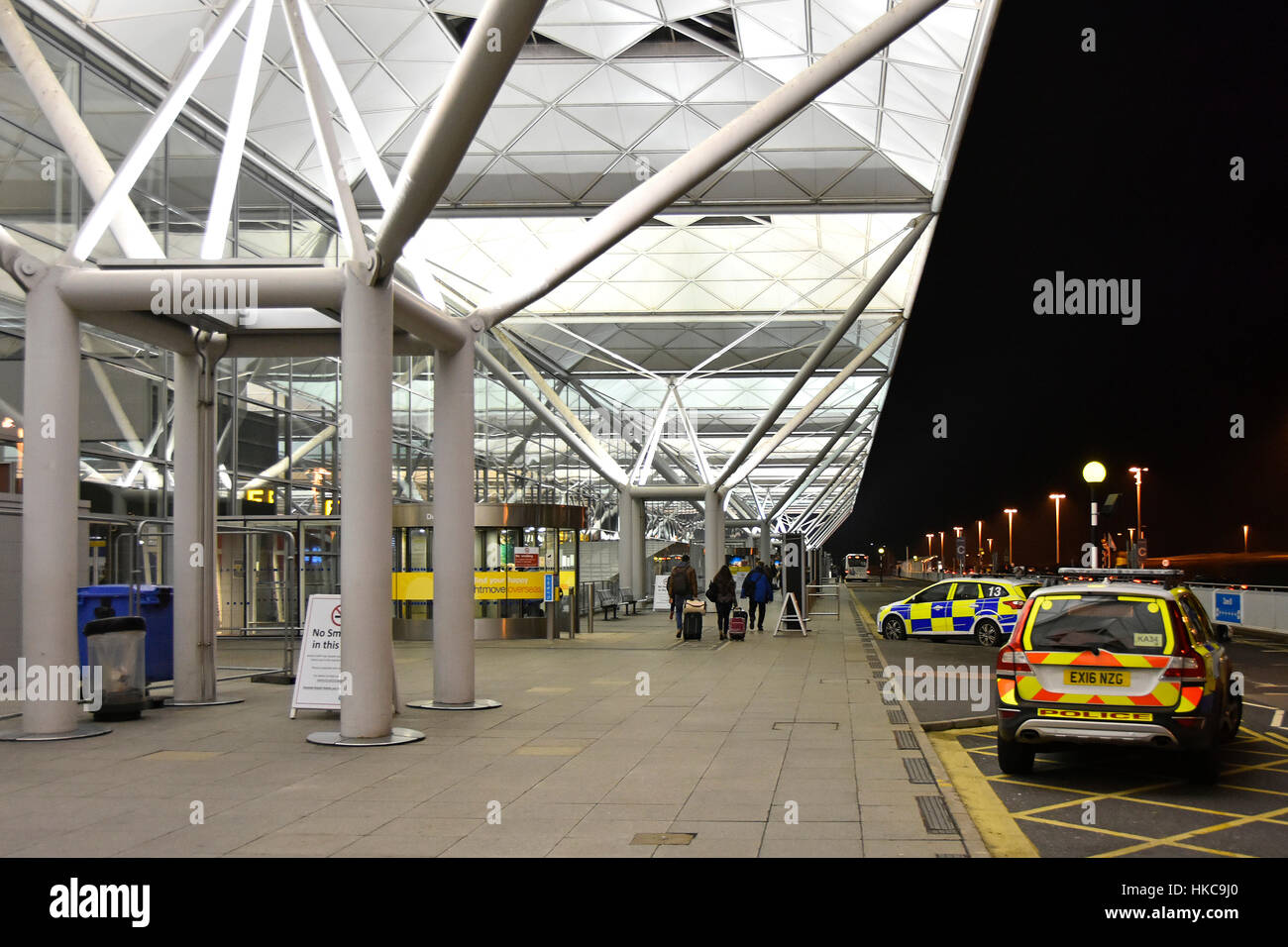 Sicurezza dell'aeroporto di notte, terminal dell'aeroporto britannico, costruzione della polizia dell'Essex e passeggeri di fronte all'aeroporto di Stansted, Inghilterra, in una fredda notte invernale Foto Stock