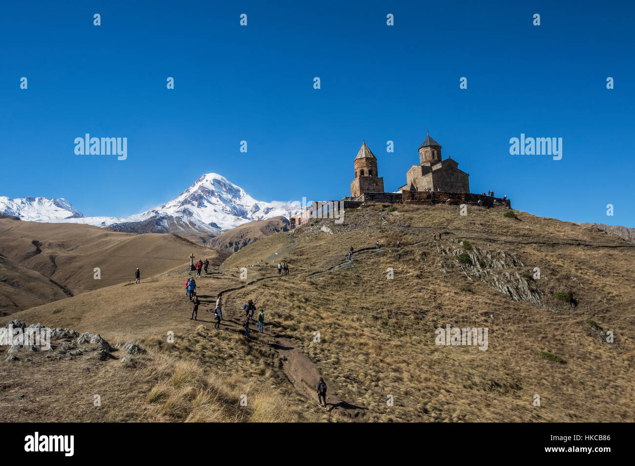 Gergeti Trinity Church con le montagne del Caucaso in background; Kazbegi, Mtskheta-Mtianeti, Georgia Foto Stock