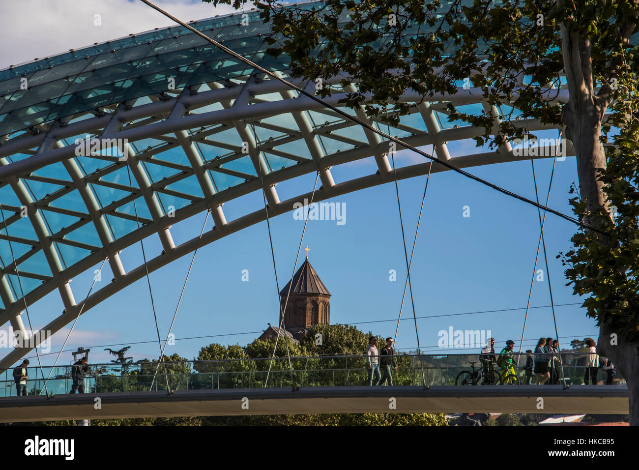 Ponte di Pace, un arco a forma di ponte pedonale al di sopra del Mtkvari Kura (Fiume) e la Chiesa di Metekhi; Tbilisi, Georgia Foto Stock