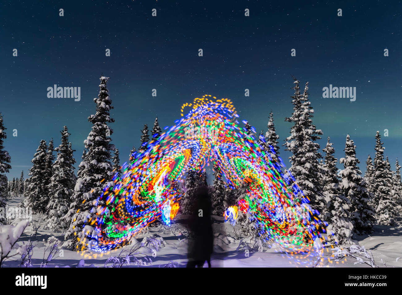 L'Aurora Borealis Danze sopra la parte superiore di Una pittura vibrante della luce a spirale, la figura blurry di Un uomo nel mezzo della pittura della luce, Moonlig... Foto Stock