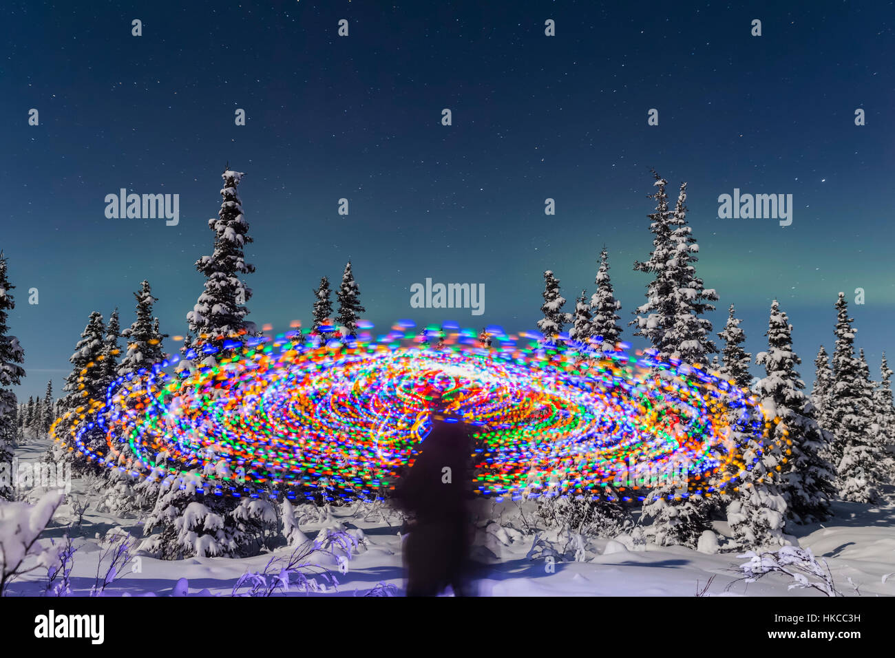 L'Aurora Borealis Danze sopra la parte superiore di Una pittura vibrante della luce a spirale, la figura blurry di Un uomo nel mezzo della pittura della luce, Moonlig... Foto Stock