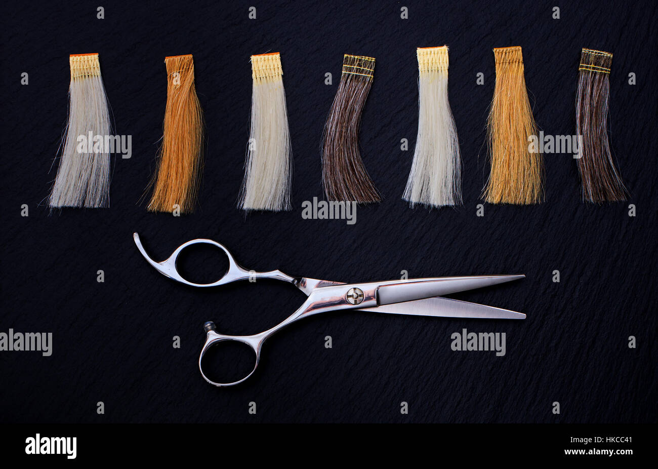 Parrucchiere accessori per la colorazione dei capelli e le estensioni di colori su uno sfondo nero. Forbici e campioni di capelli Foto Stock