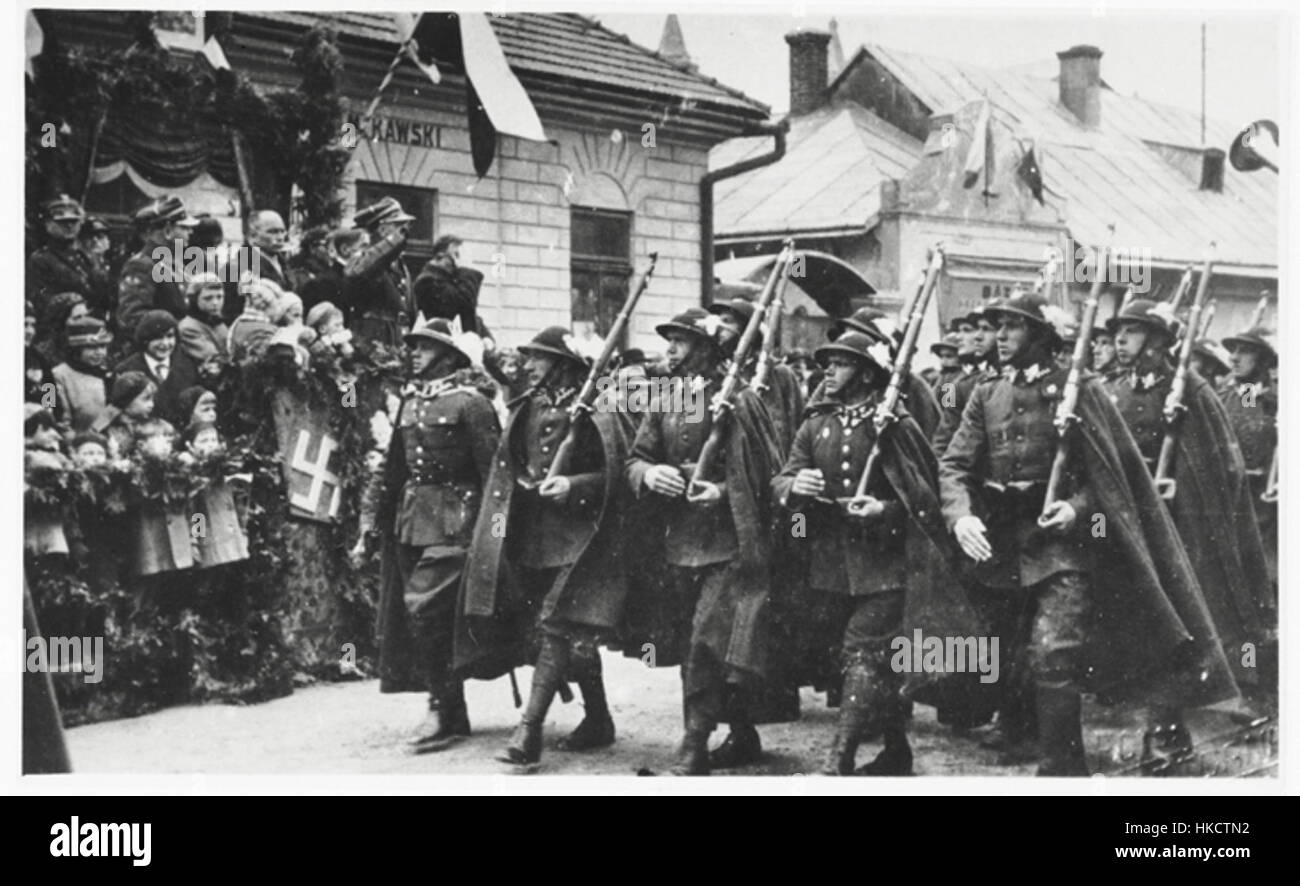 Questa opera d'arte del 1936 ritrae una marcia lungo una strada a Sanok, che mostra scene storiche risalenti al periodo precedente alla seconda guerra mondiale. La svastica, un simbolo usato dalla Germania nazista, appare nel dipinto, segnando un periodo di intenso cambiamento politico e sociale. Foto Stock