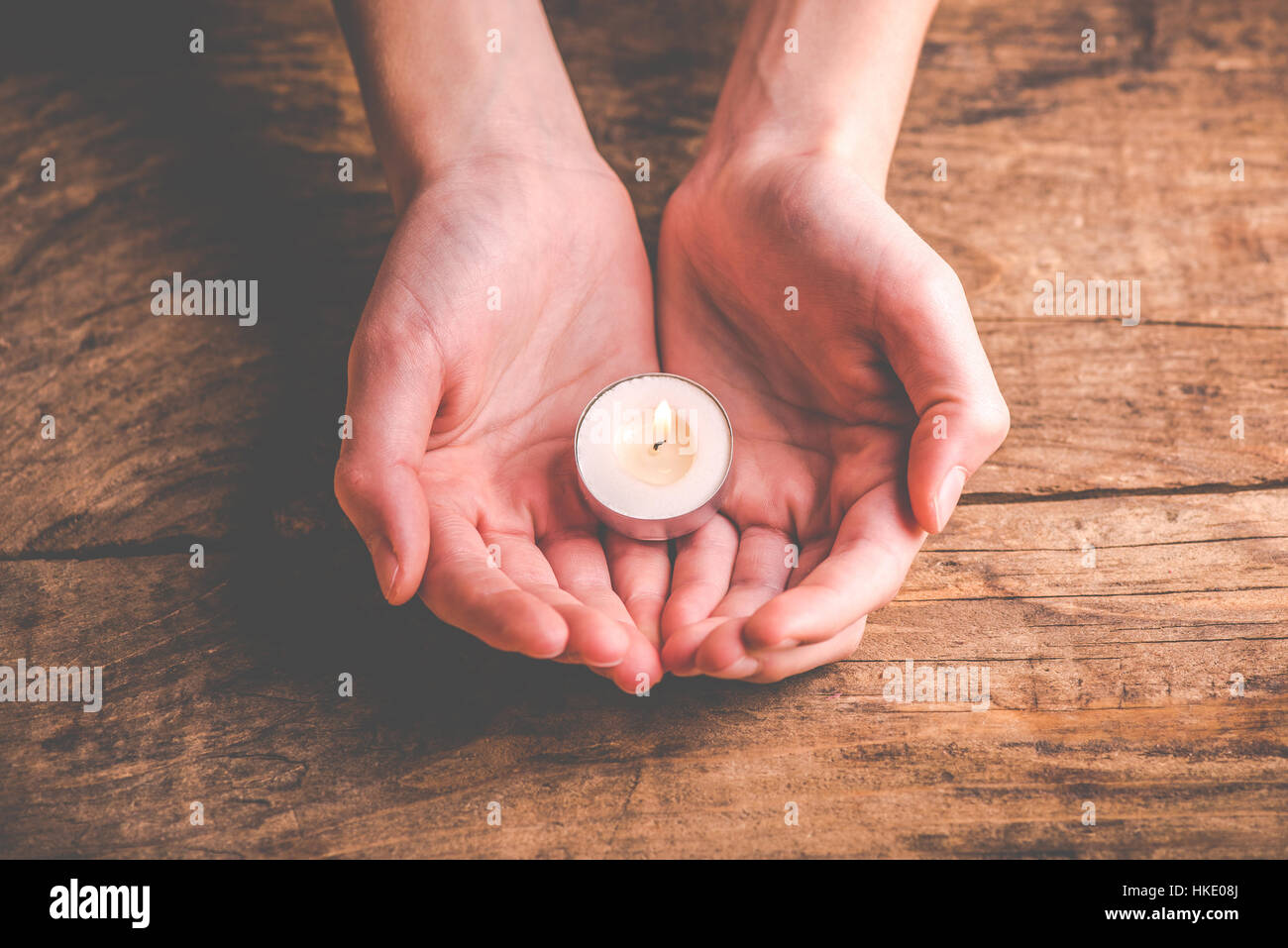 Mani che proteggono la fiamma di una candela Foto Stock