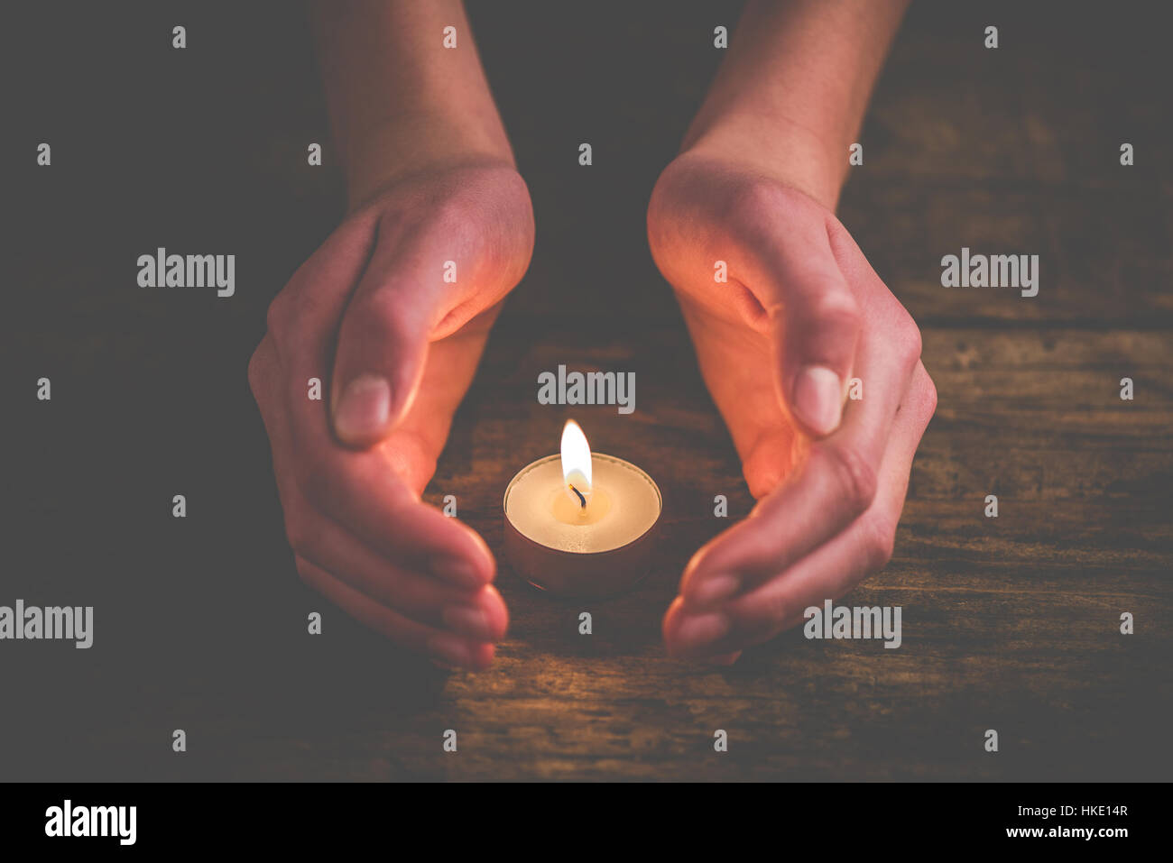 Mani che proteggono la fiamma di una candela Foto Stock