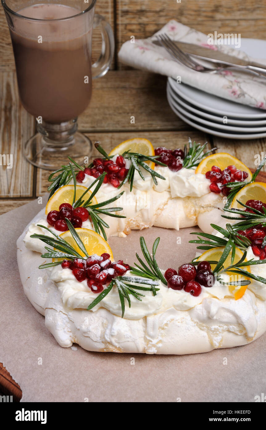 Pavlova torta a forma di una ghirlanda di Natale di meringa con panna, melograno, cranberry, rametti di rosmarino Foto Stock