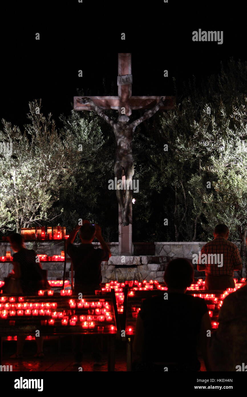 Pellegrini venuti alla luce di una candela davanti alla Croce vicino al Saint James chiesa. Foto Stock