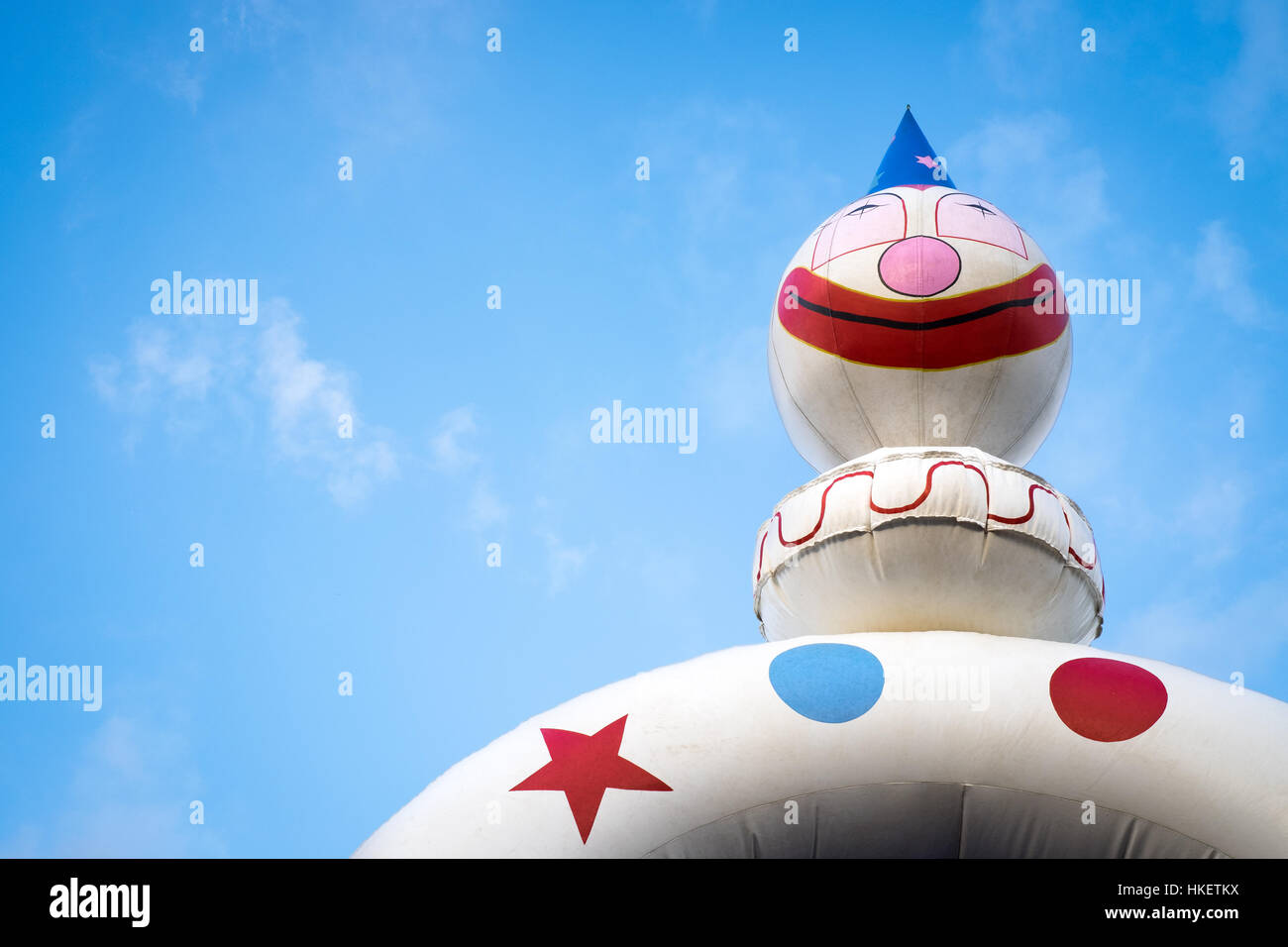 Clown jumping castle contro il cielo blu con nuvole di offset dello spazio di copia Foto Stock