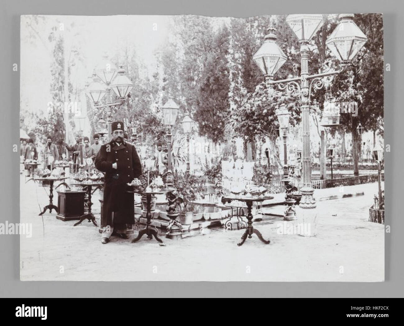 Questo dipinto ad olio di Mozaffar al-DIN Shah, creato da un artista sconosciuto, raffigura lo scià in posa davanti a una festa in un giardino di palazzo. Le opere d'arte catturano l'atmosfera reale e la grandezza della vita di corte persiana durante il suo regno all'inizio del XX secolo. Foto Stock