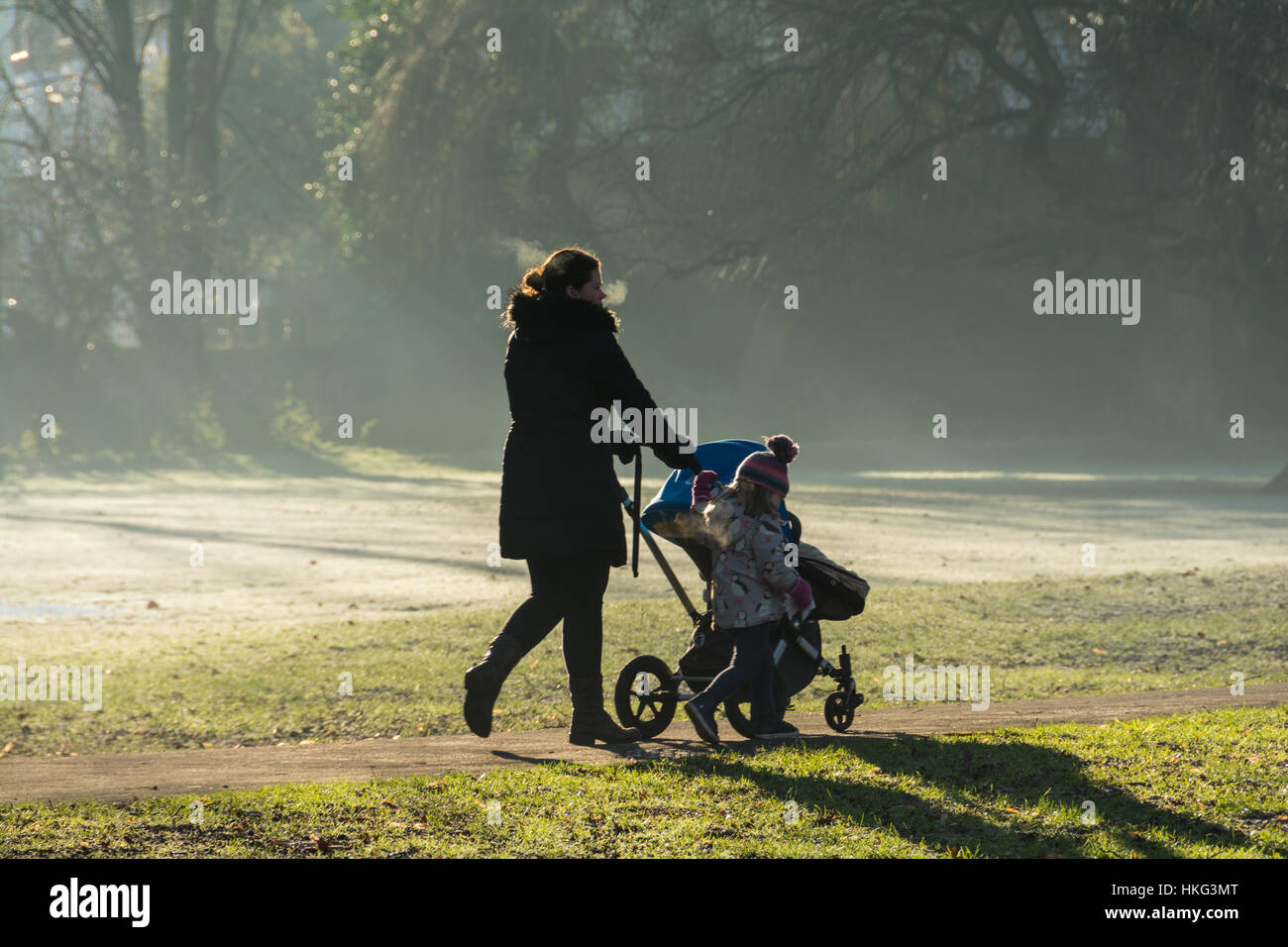 Una mamma a piedi i suoi figli alla scuola materna su un gelido mattino. Foto Stock
