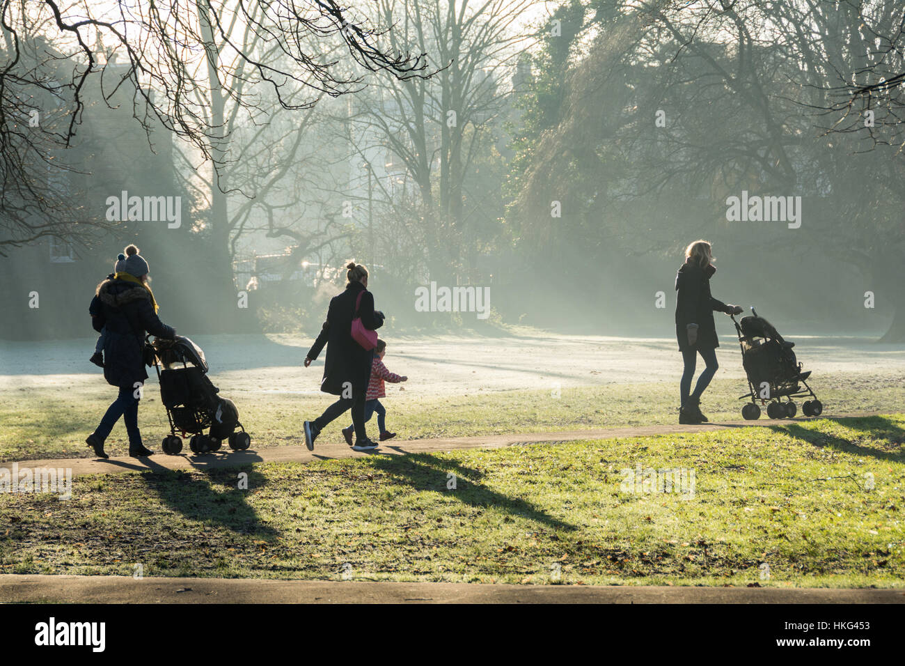 Scuola di corsa - le mamme che camminano i loro bambini a scuola in una mattinata gelida di inverno. Foto Stock