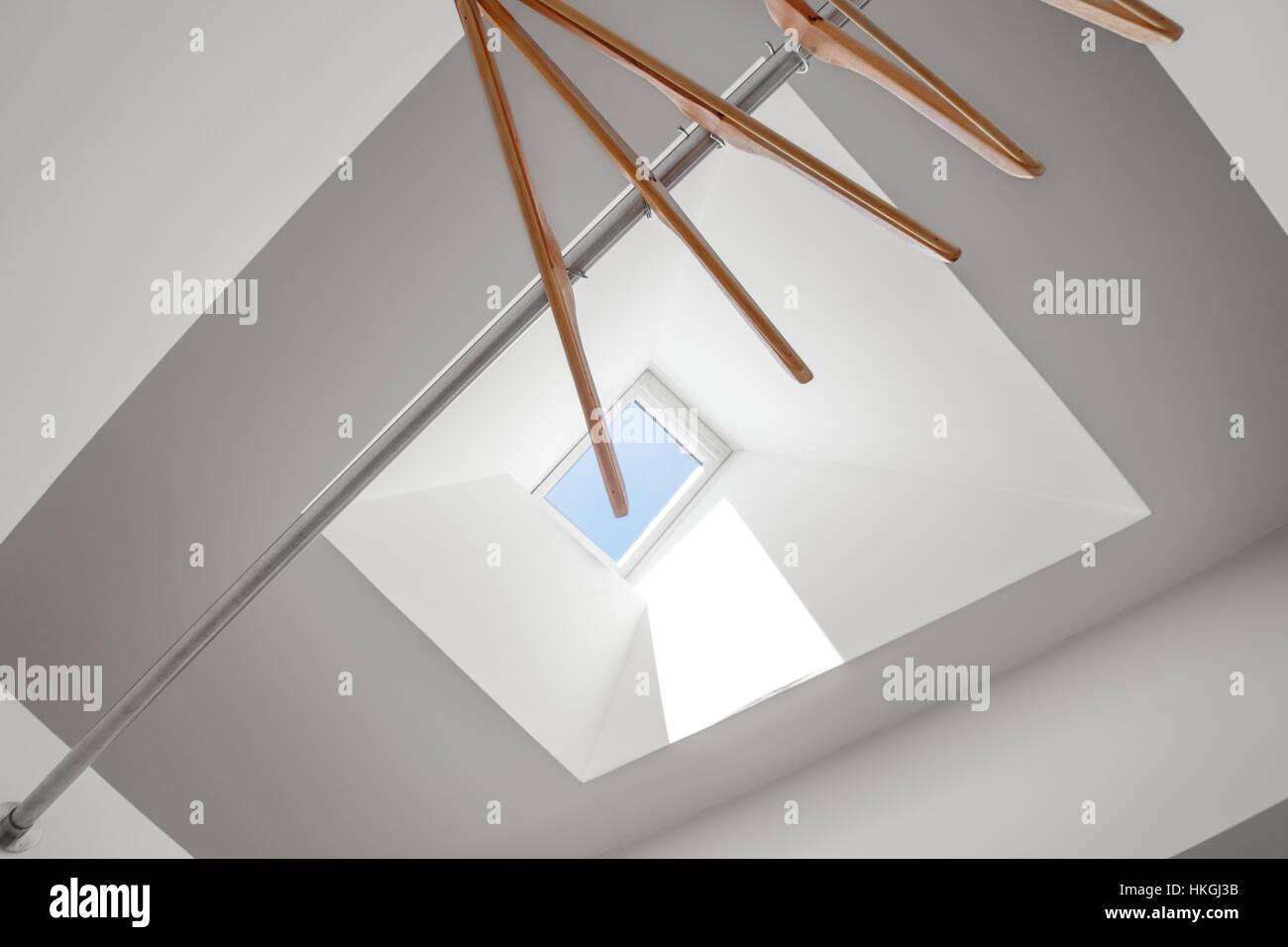 Legno appendiabiti sotto una luminosa finestra lucernario Foto Stock