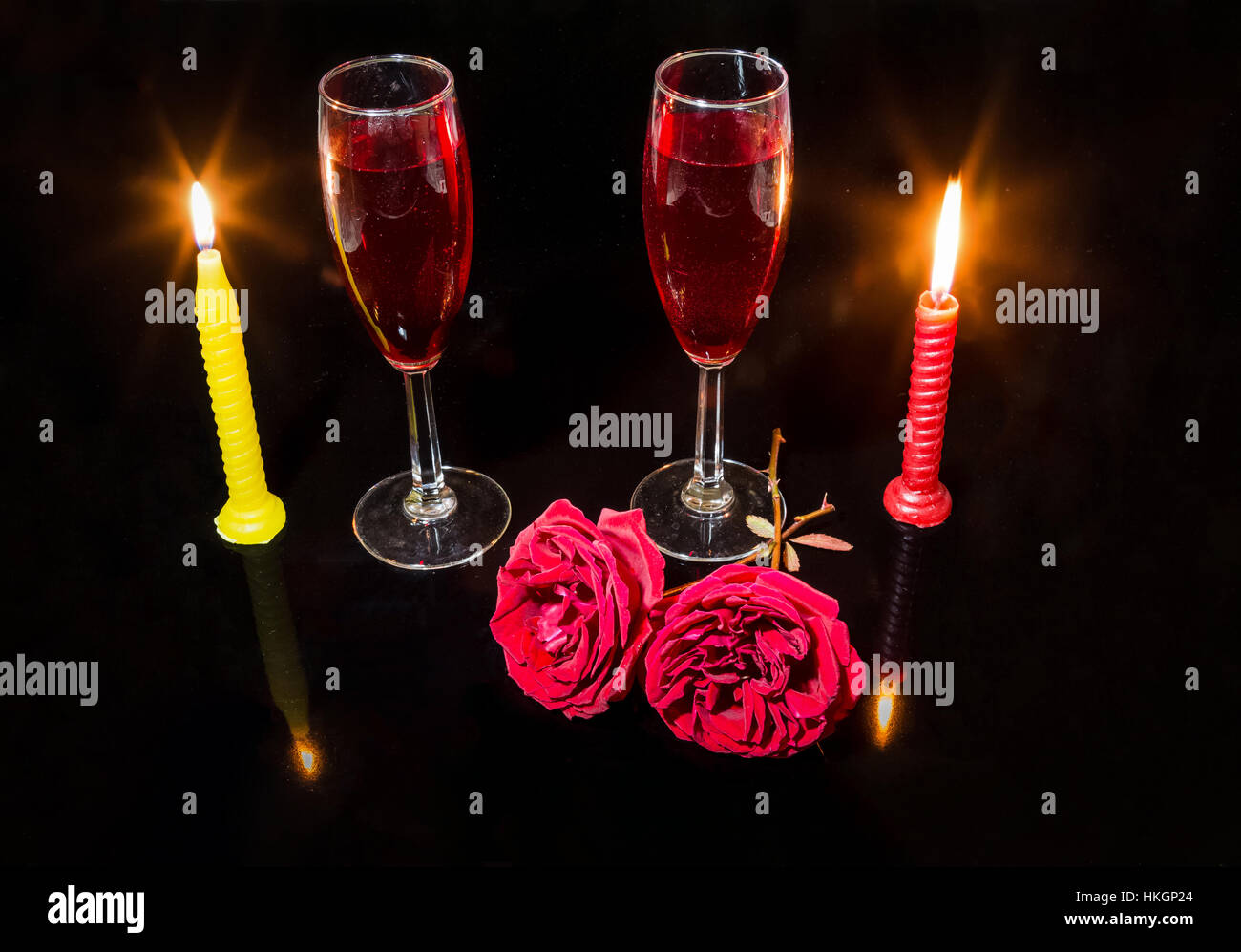 Impostazione romantica con candele accese rose rosse e vino rosso bicchieri in uno sfondo scuro. Foto Stock