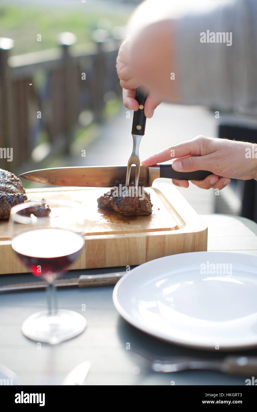 Mani il taglio di carne arrosto al ristorante. carving set, tagliere, bicchiere  di vino e cibo Foto stock - Alamy