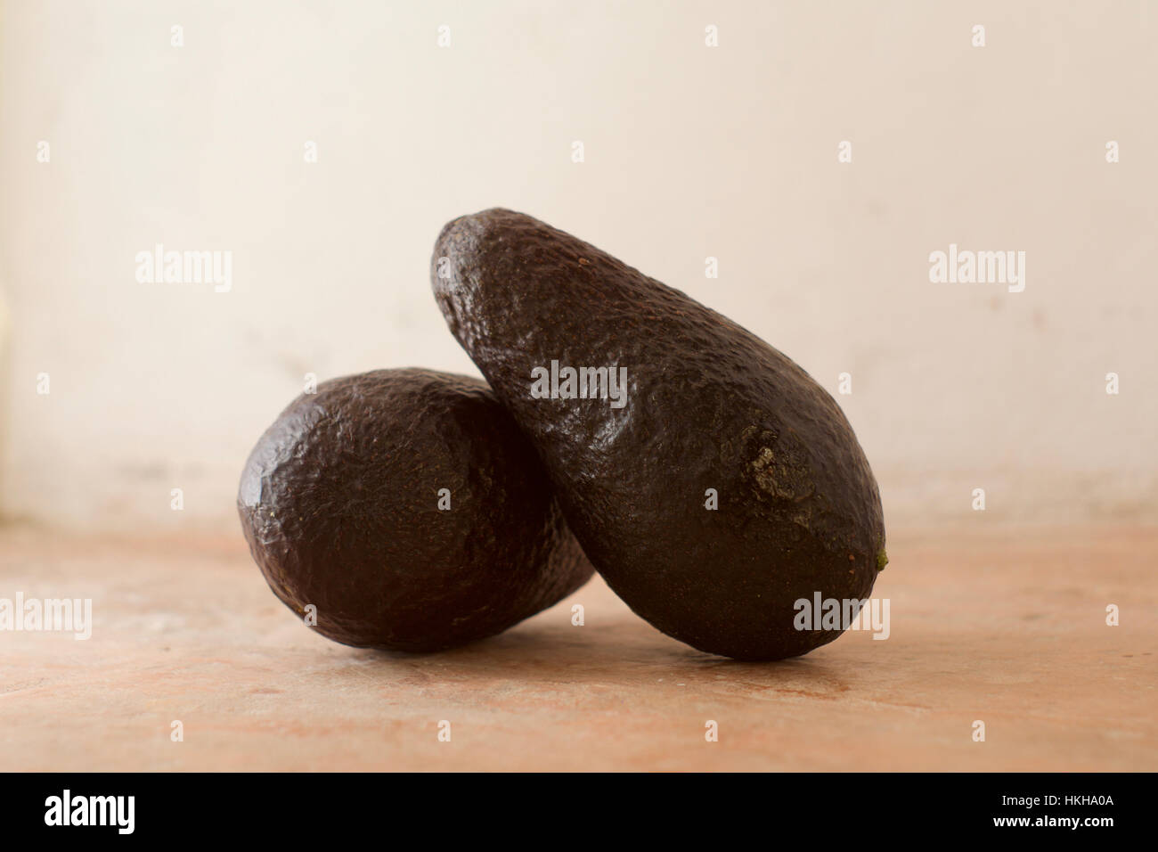 Due avocadi Hass contro un sfondo rustico Foto Stock