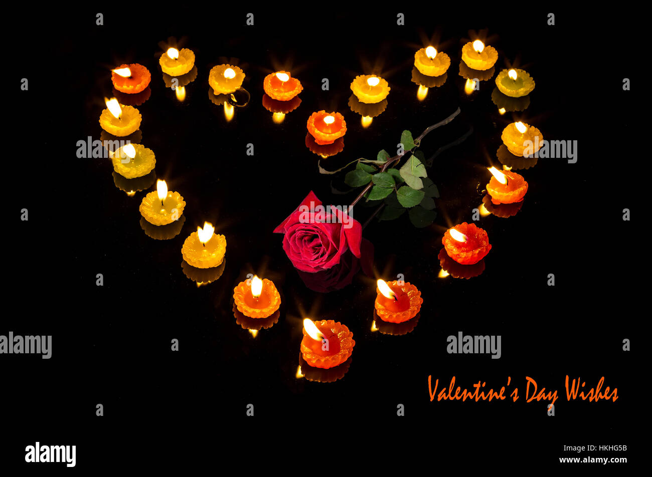 Romantico San Valentino di configurazione con le candele accese in forma di cuore e una rosa rossa isolato in sfondo nero - rapporto d'amore. Foto Stock