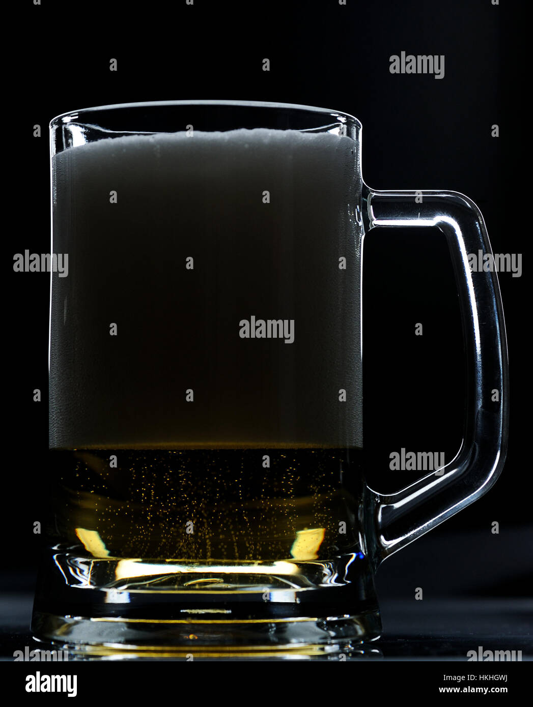 Vetro con birra pieno di schiuma nella metà su sfondo nero Foto Stock