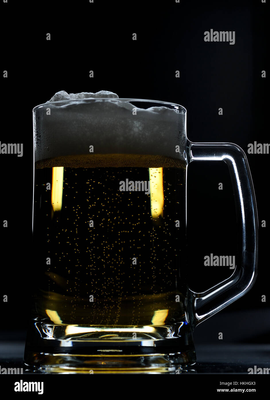 Bicchiere di birra marrone con schiuma su sfondo nero Foto Stock