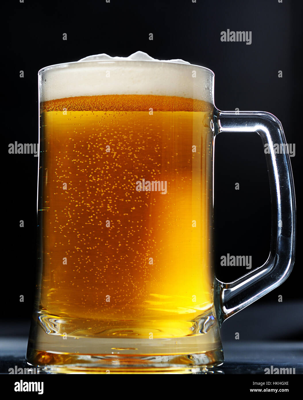 Bicchiere di birra marrone con schiuma su sfondo nero Foto Stock