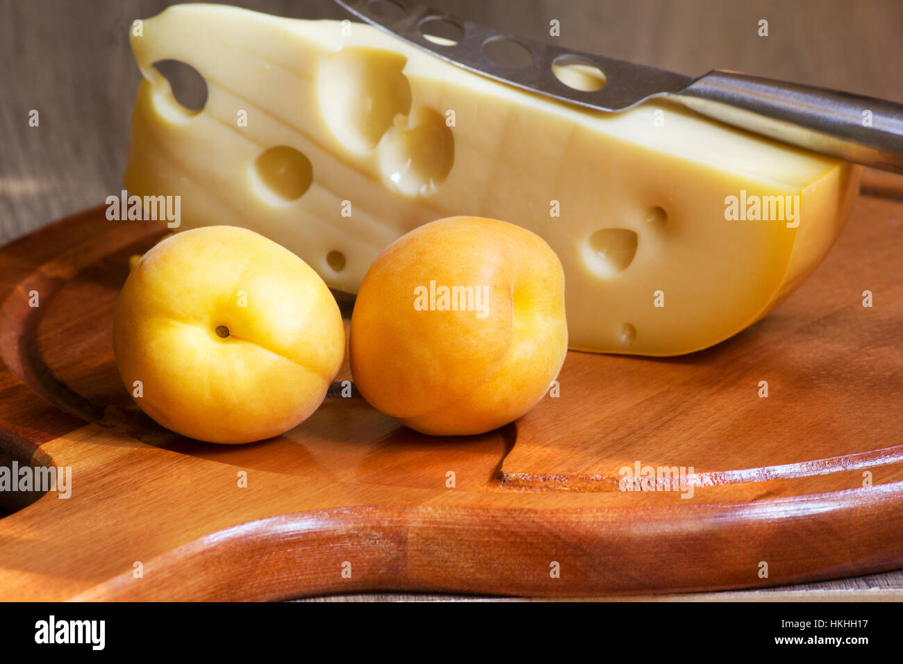 Il formaggio e le albicocche su legno scheda di formaggio Foto Stock