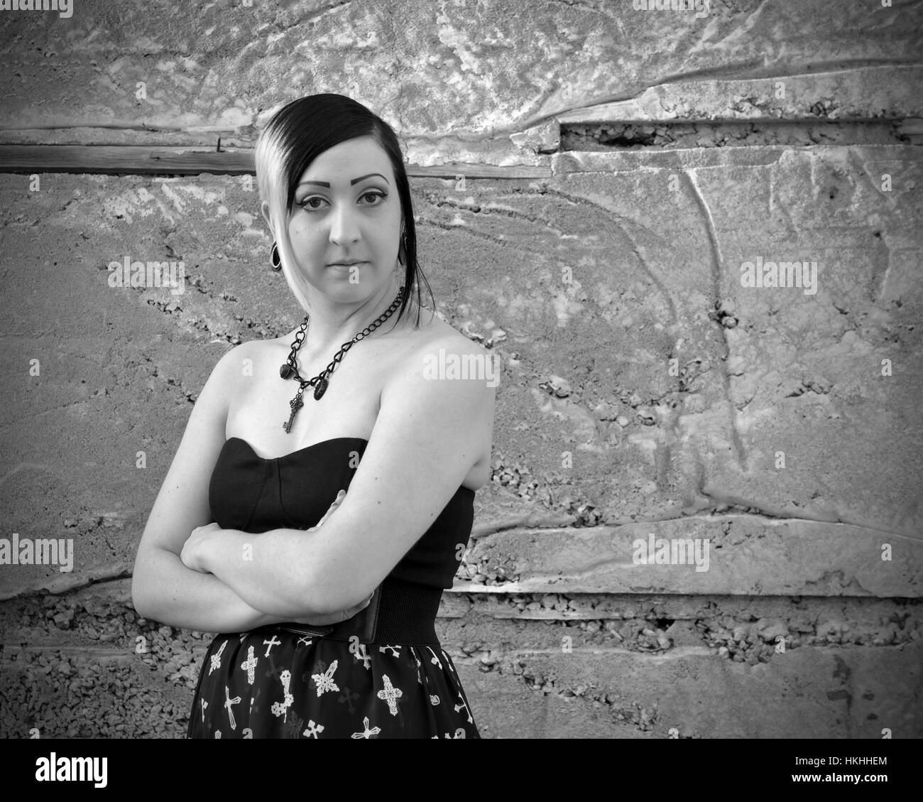 Ritratto di bella, giovane gothic brunet modello femminile in posa contro il muro di cemento- in bianco e nero il rendering Foto Stock