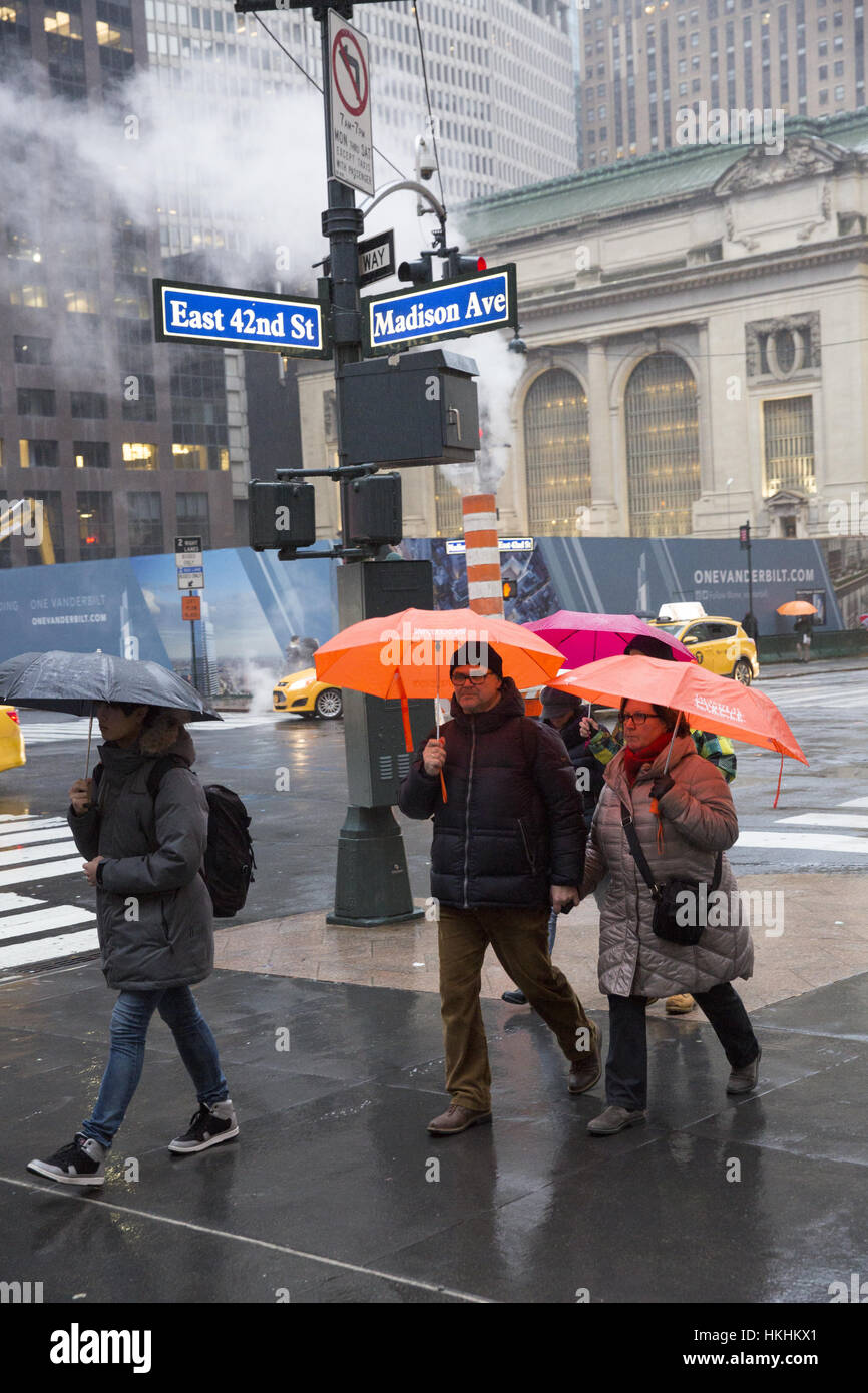 La gente a piedi lungo la 42nd Street a Madison Avenue nel cuore di Manhattan in una piovosa giornata d'inverno. Foto Stock