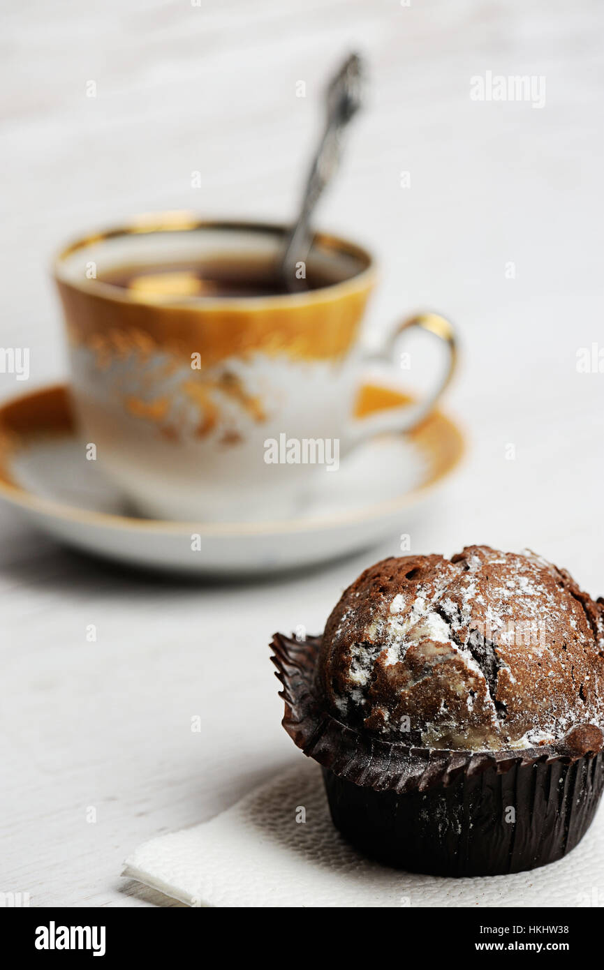 Tortina di cioccolato sulla tavola di legno con sfocato tazza di tè sul retro Foto Stock