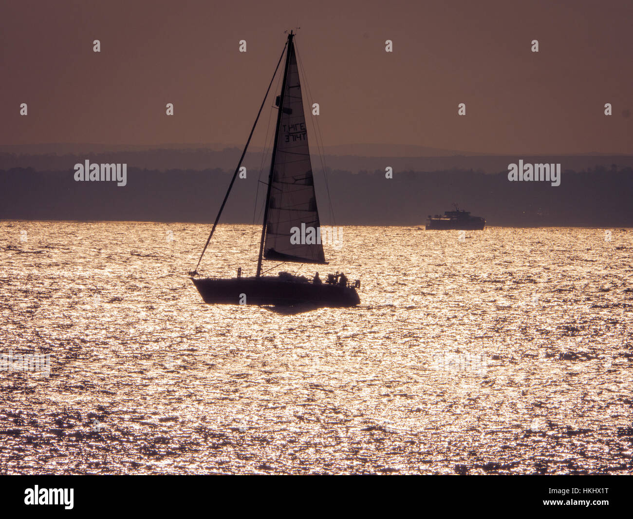 Una barca a vela al tramonto nel Solent, Inghilterra Foto Stock