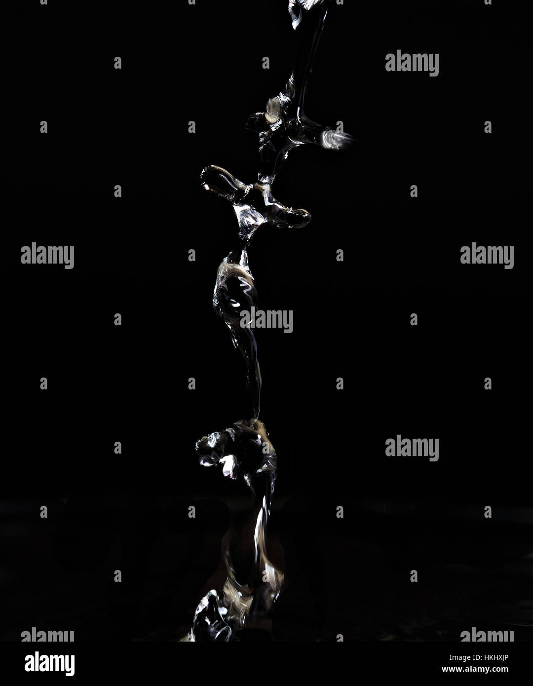 Lungo splash acqua scende isolata su sfondo nero Foto Stock