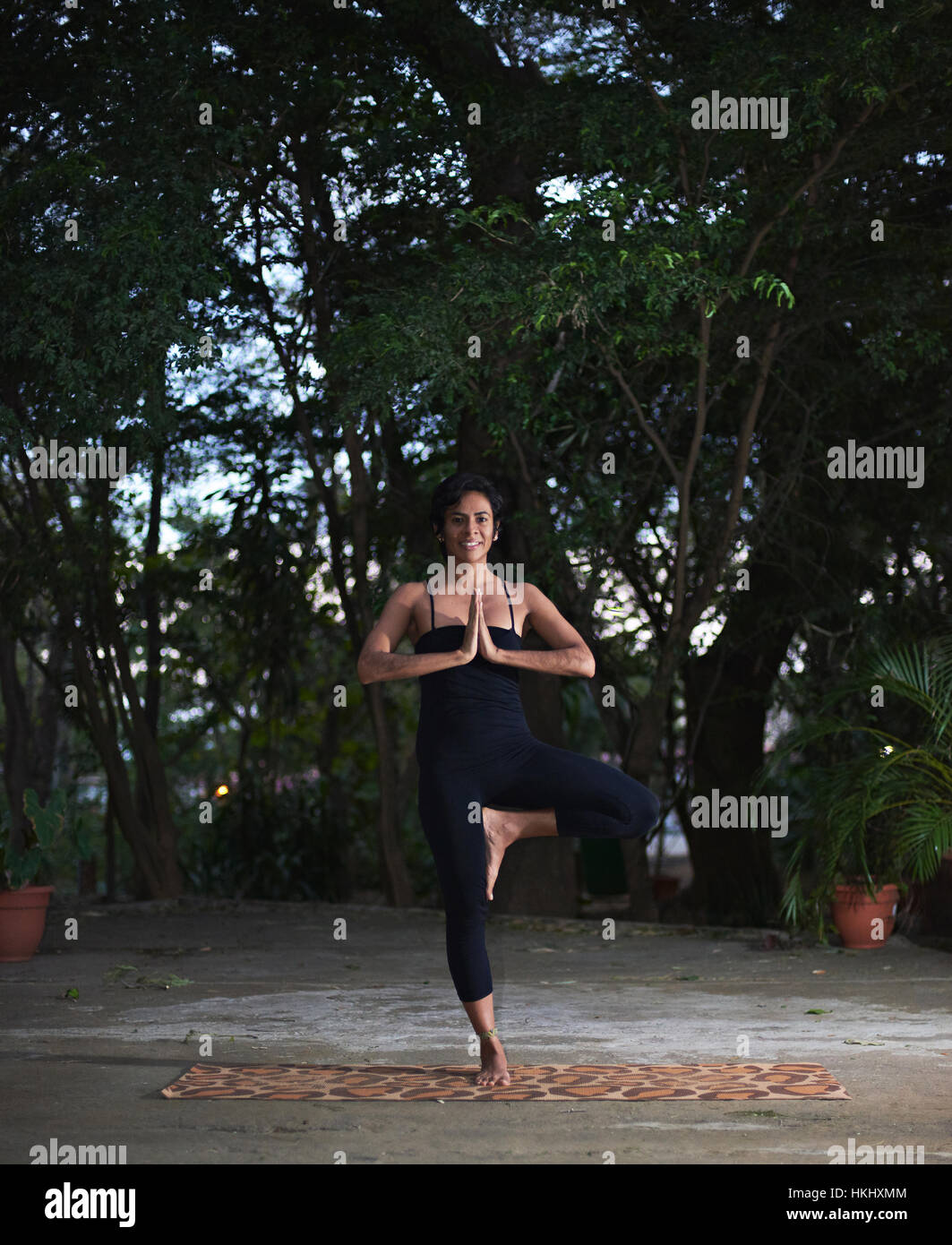 Donna fare yoga pone nel giardino della sera Foto Stock