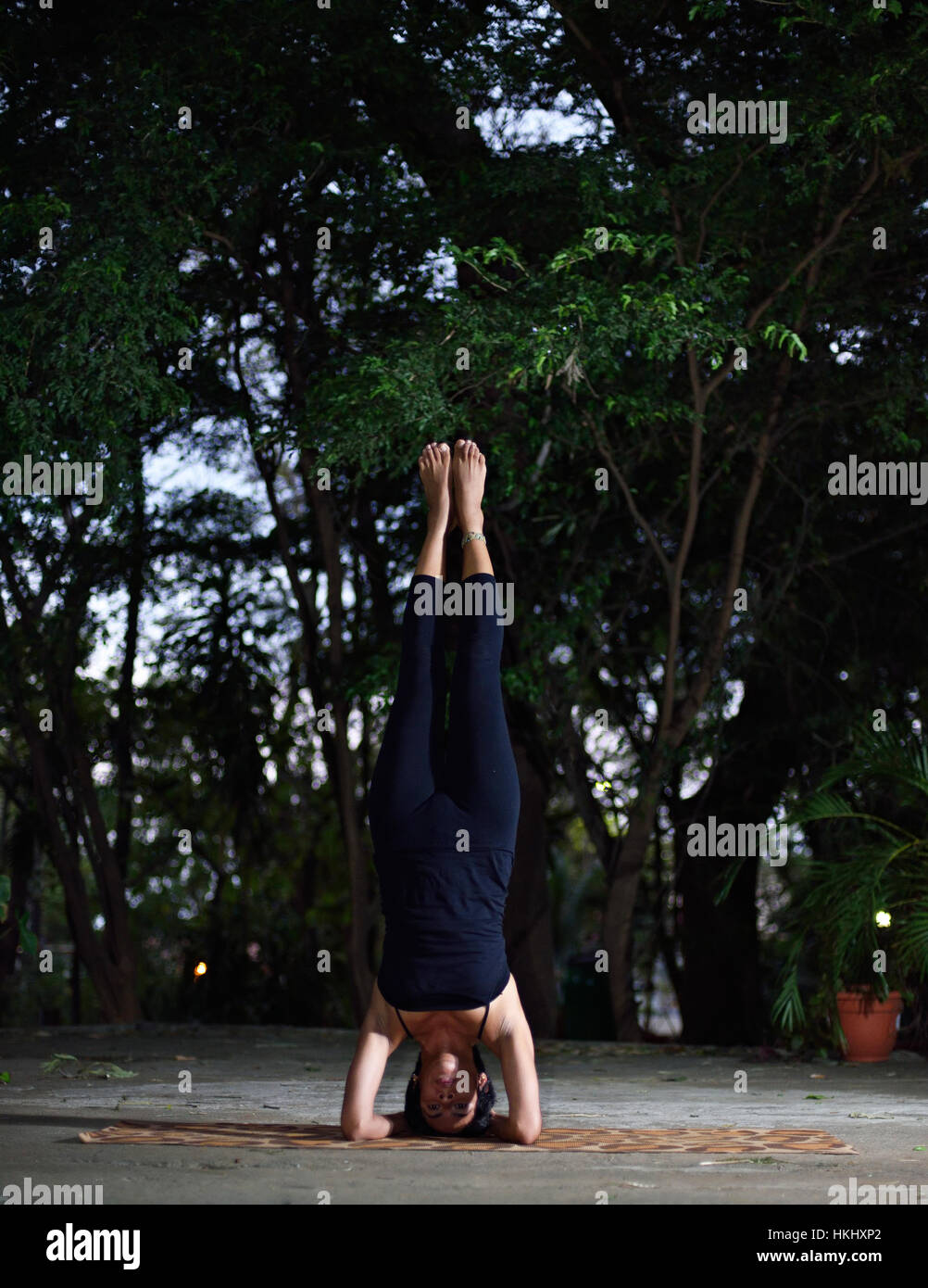 Latino yoga ragazza stare sulla testa in giardino Foto Stock