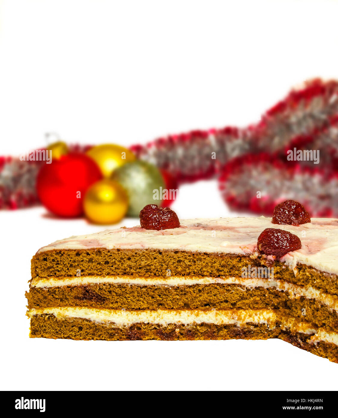 Su uno sfondo bianco torta di compleanno e unfocused orpelli natalizi con le palle colorate Foto Stock