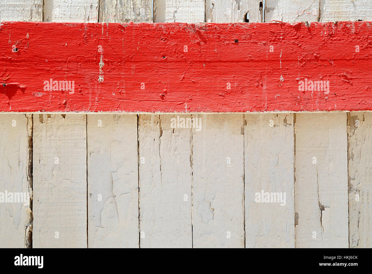 Orizzontale striscia rossa del dipinto su tavola di legno contro il recinto bianco coperto con incrinato sbucciato vernice vecchia. Concetto di sfondo con spazio di copia Foto Stock