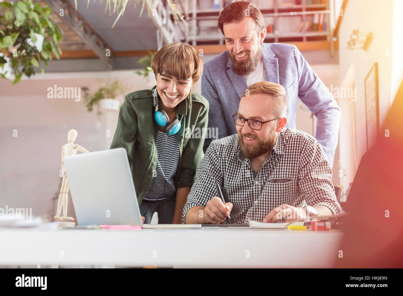 Sorridente professionisti del design con tavoletta grafica al computer portatile in ufficio Foto Stock